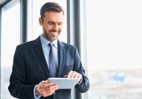 Happy businessman using digital tablet standing in office